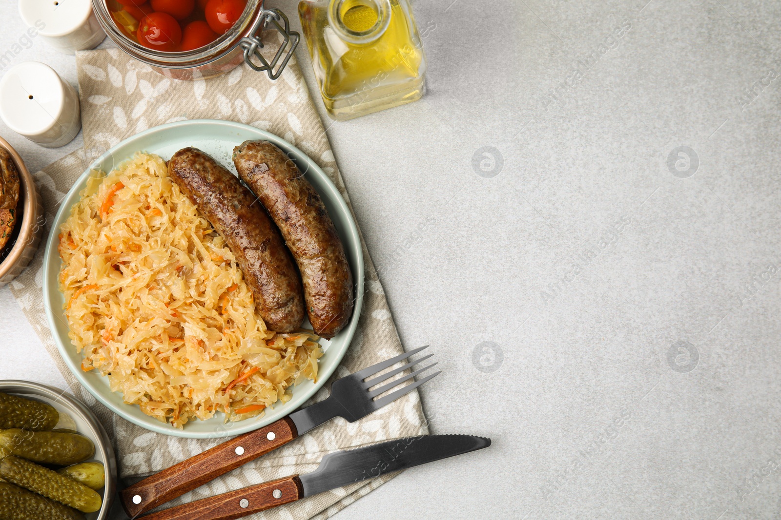 Photo of Plate with sauerkraut and sausages served on light grey table, flat lay. Space for text