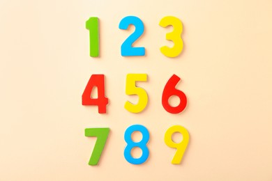 Colorful numbers on beige background, flat lay