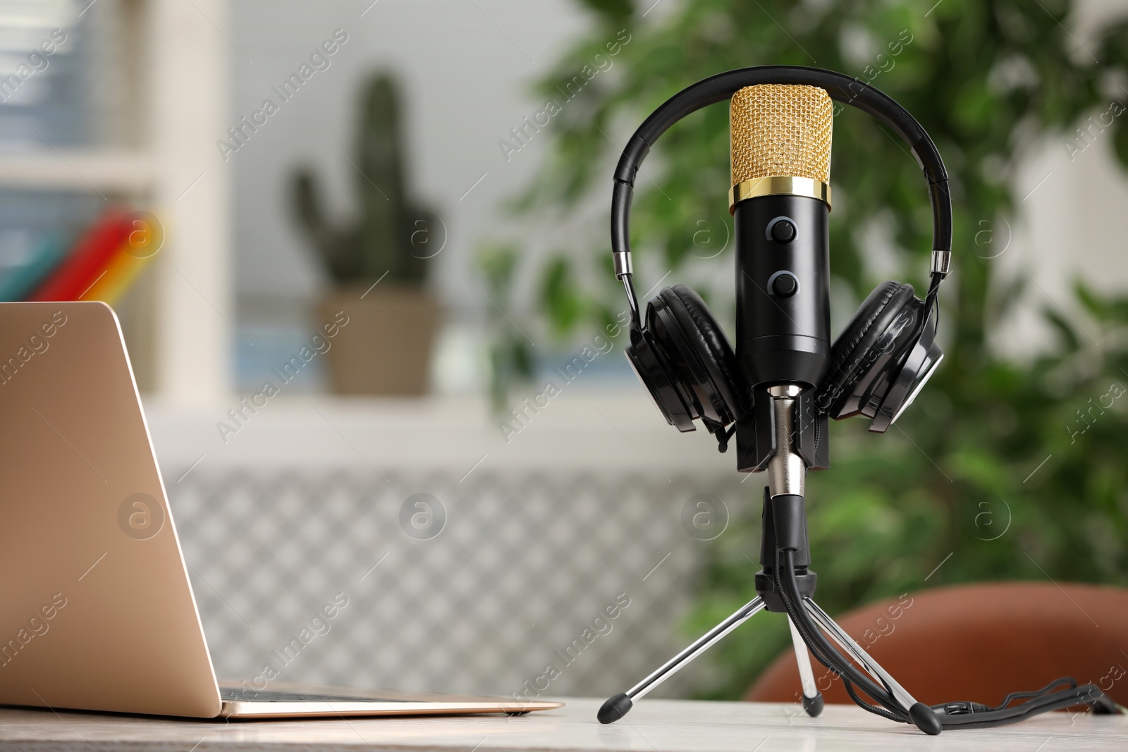 Photo of Microphone, modern headphones and laptop on table indoors