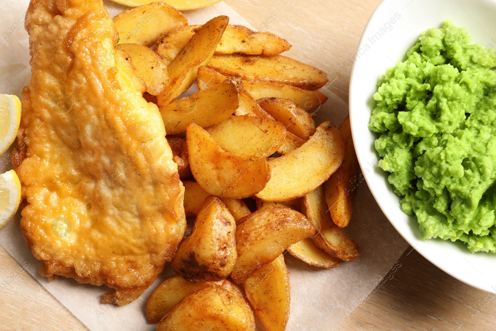 Photo of British traditional fish and potato chips on wooden background, closeup