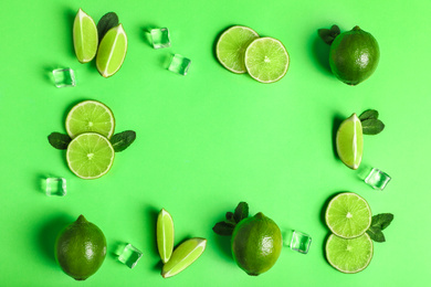 Photo of Flat lay composition with fresh juicy limes on light green background, space for text