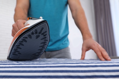 Photo of Man ironing shirt on board at home, closeup. Space for text