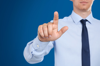 Businessman touching something against blue background, focus on hand
