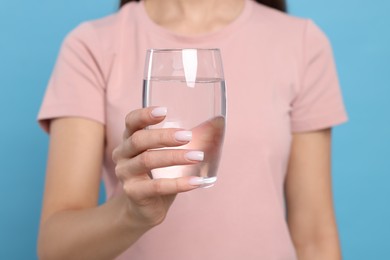 Healthy habit. Closeup of woman holding glass with fresh water on light blue background