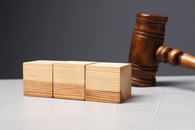 Law. Blank wooden cubes and gavel on light table against gray background