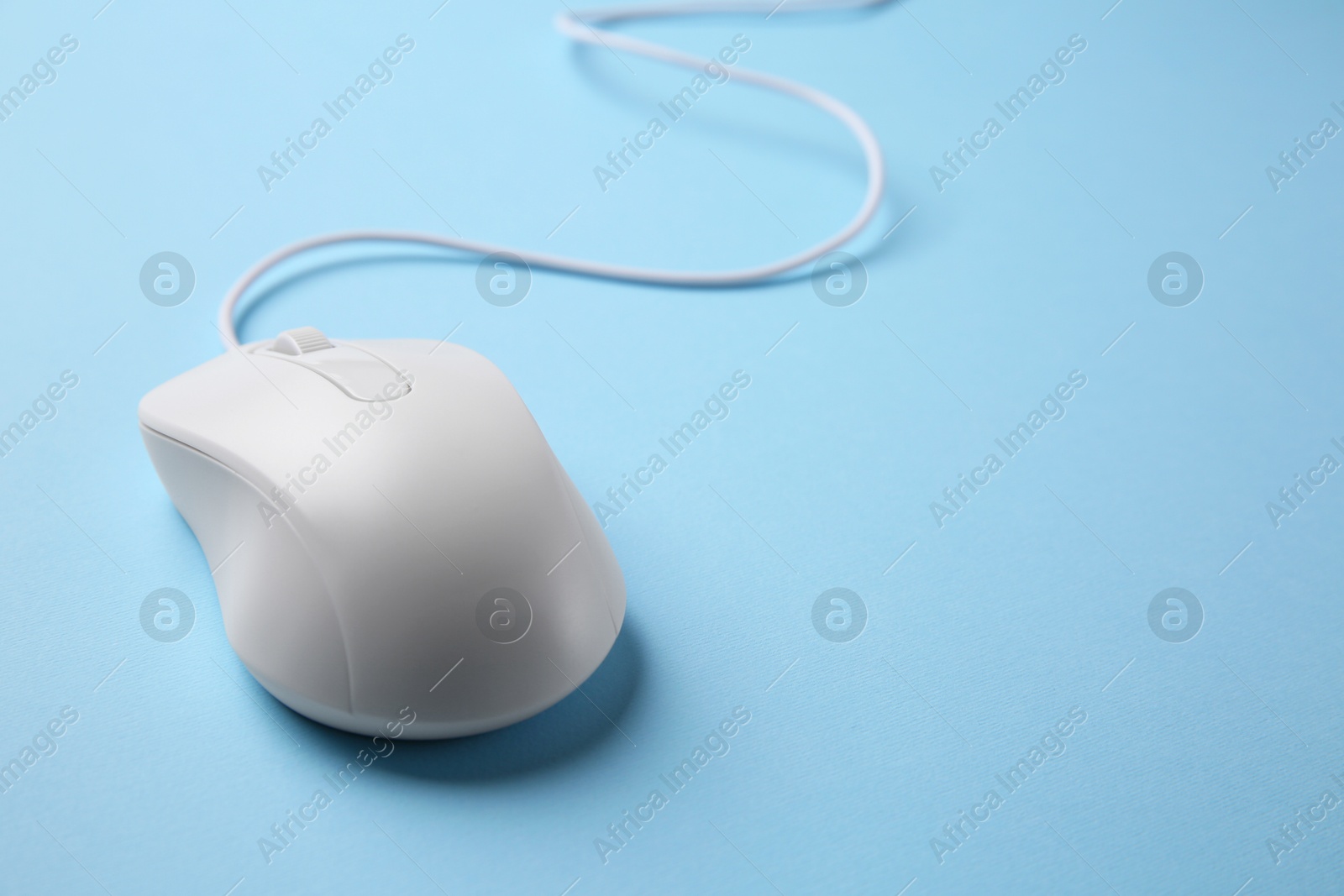 Photo of One wired mouse on light blue background, closeup. Space for text