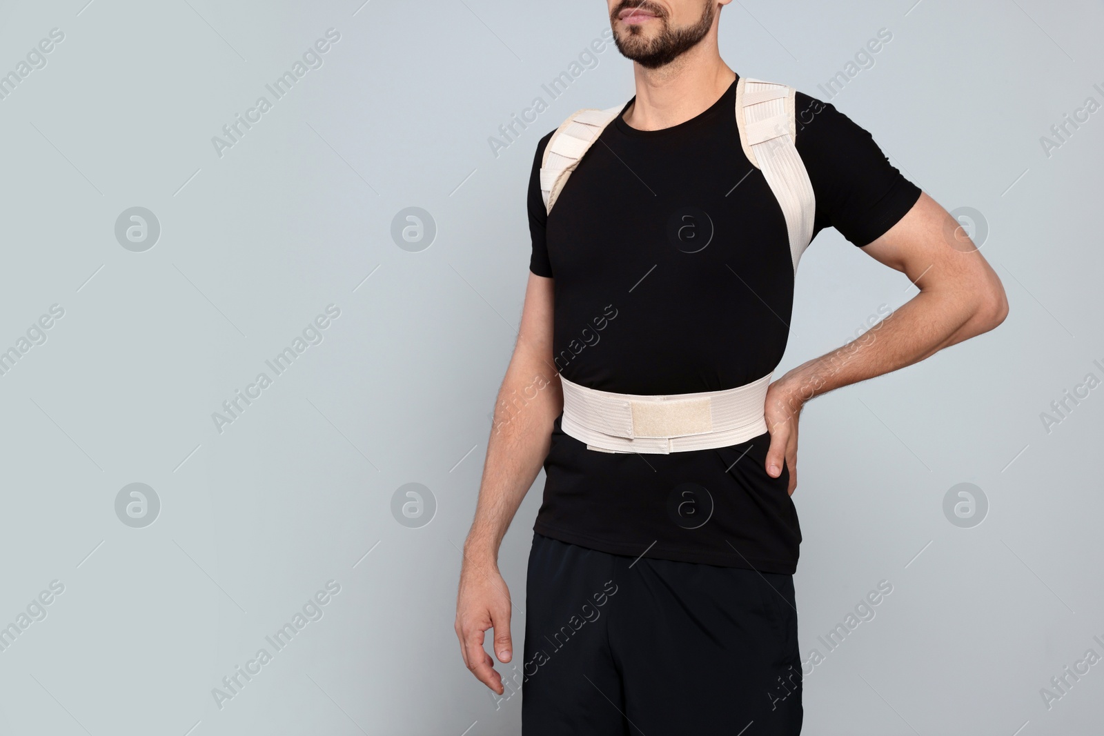 Photo of Closeup view of man with orthopedic corset on grey background, space for text