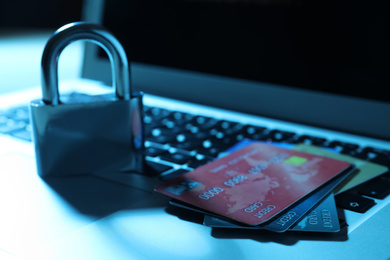 Photo of Credit cards, lock and laptop on table, closeup. Cyber crime