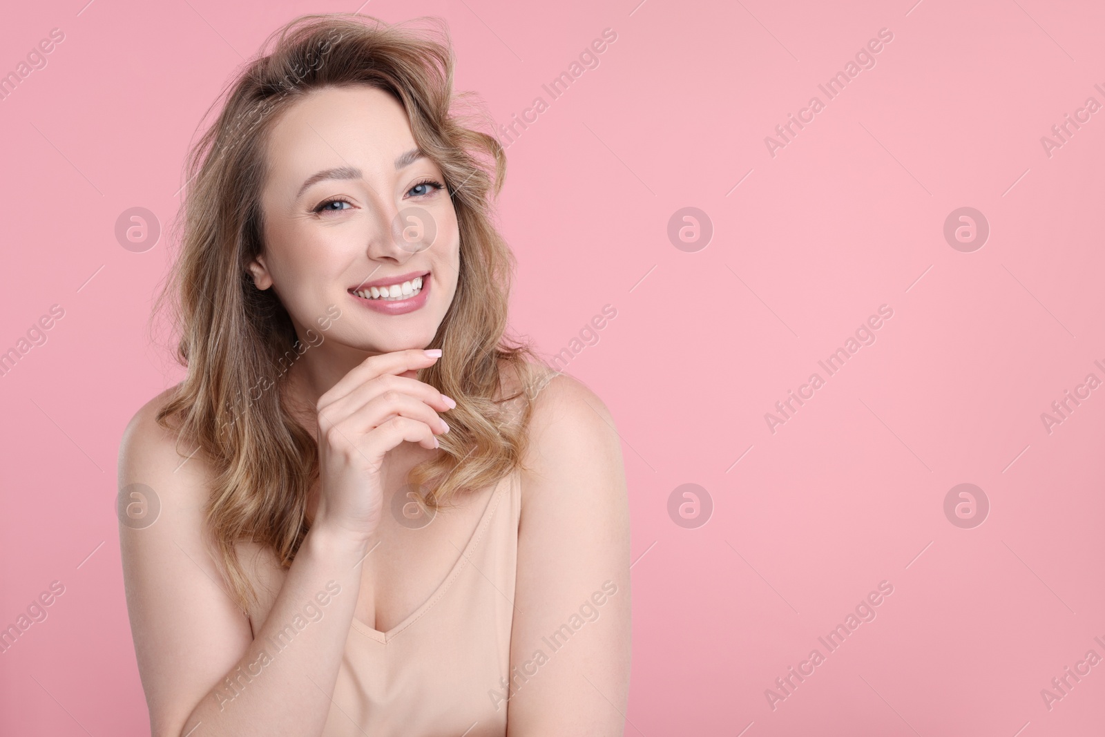 Photo of Portrait of smiling woman on pink background. Space for text