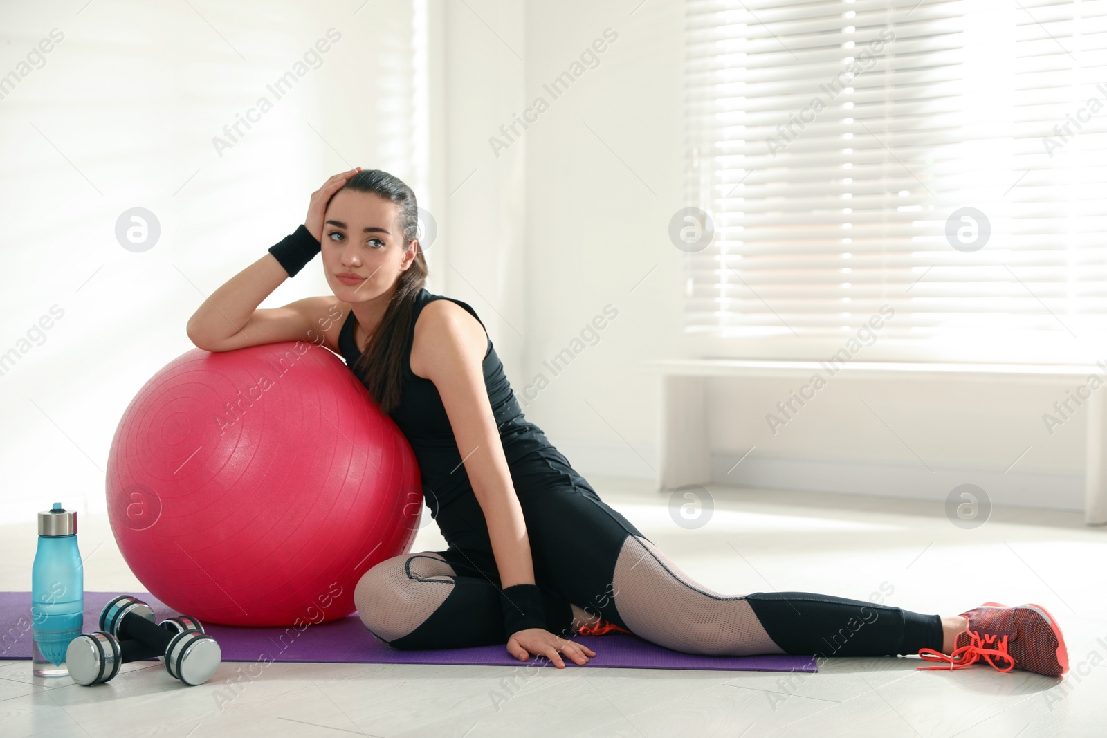 Photo of Lazy young woman with sport equipment indoors. Space for text