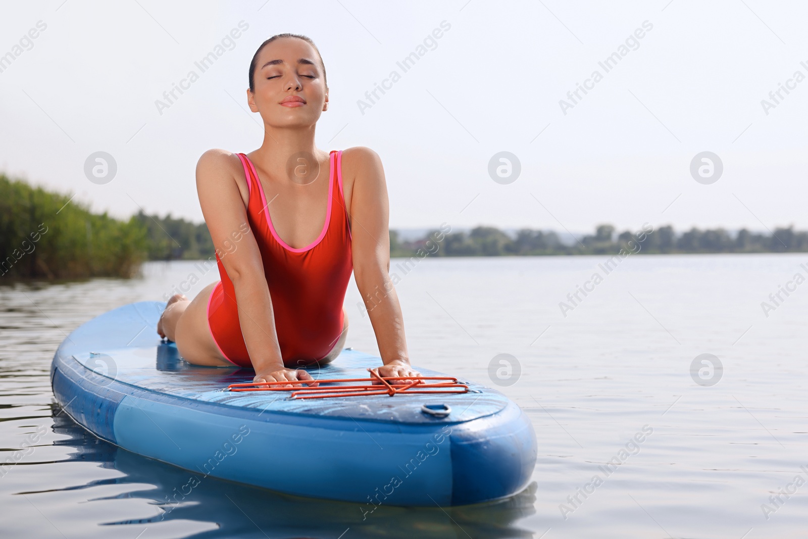 Photo of Woman practicing yoga on light blue SUP board on river, space for text