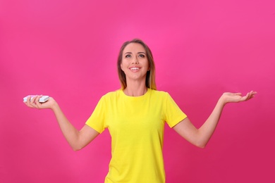 Photo of Young woman with air conditioner remote on hot pink background