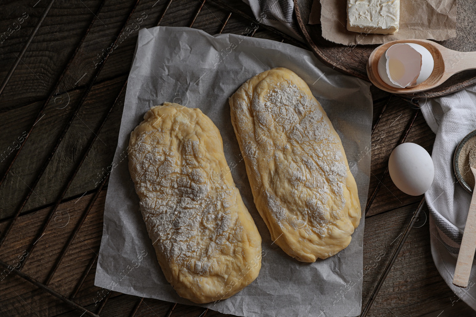 Photo of Raw dough for ciabatta and flour on wooden table, flat lay