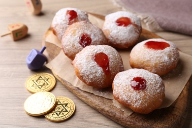 Hanukkah donuts, dreidels and coins on wooden table