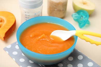 Bowl with healthy baby food on color table