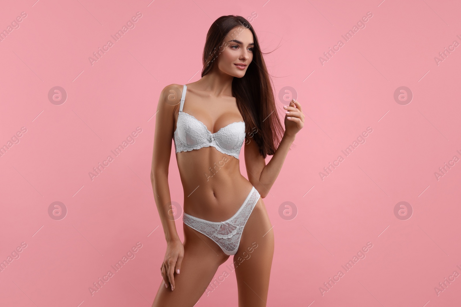 Photo of Young woman in elegant white underwear on pink background