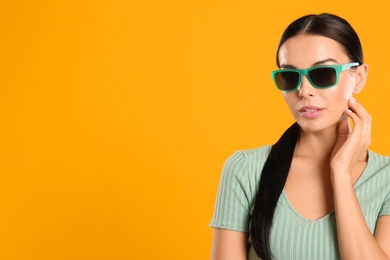 Photo of Beautiful woman wearing sunglasses on yellow background. Space for text