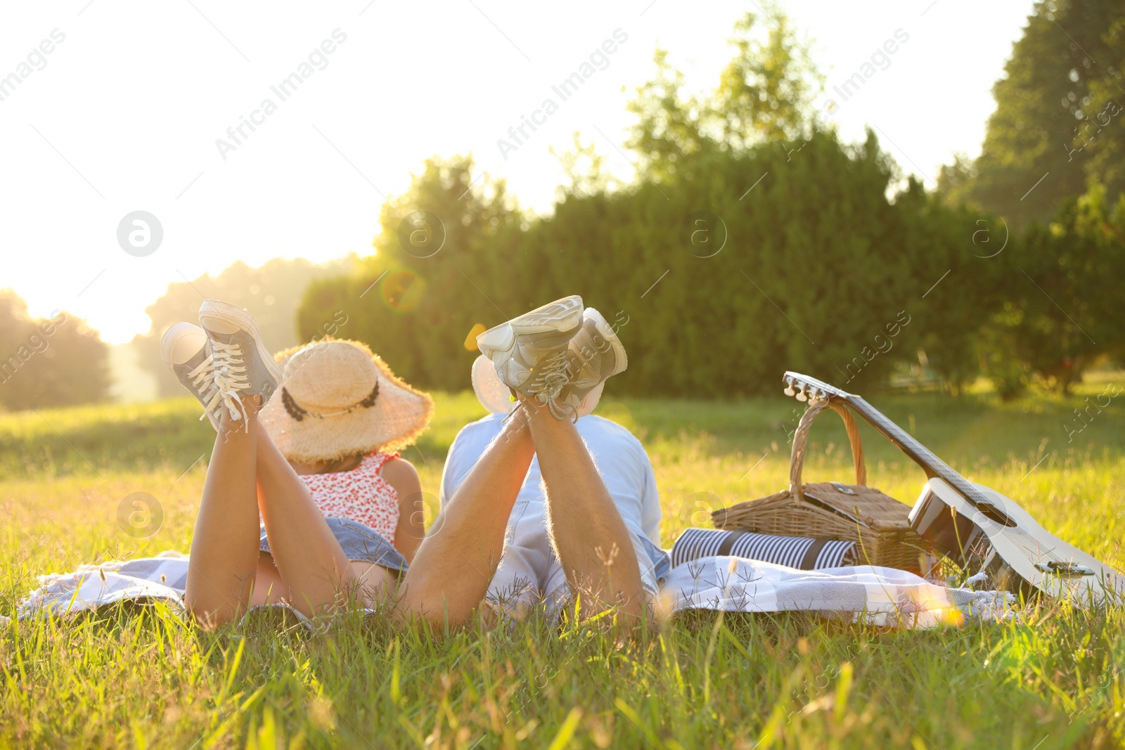 Photo of Happy couple with guitar and picnic basket in park on sunny day