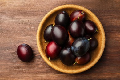 Tasty ripe plums on wooden table, flat lay