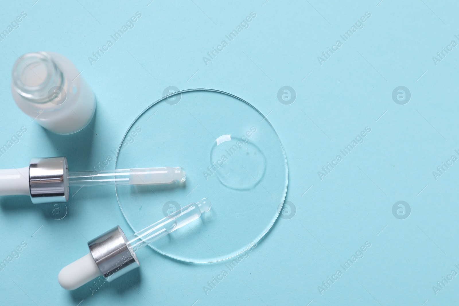 Photo of Sample of cosmetic serum, bottle and pipettes on light blue background, flat lay. Space for text