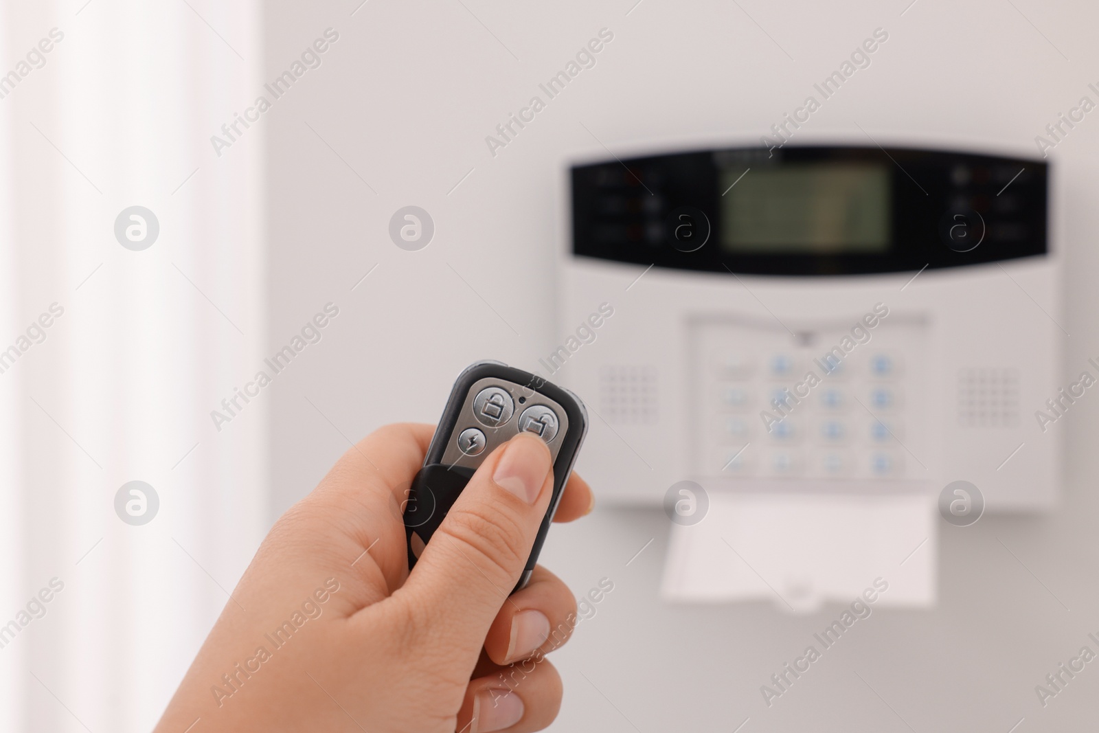 Photo of Home security system. Woman using alarm key fob indoors, closeup
