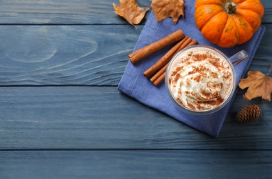 Photo of Delicious pumpkin latte on blue wooden table, flat lay. Space for text