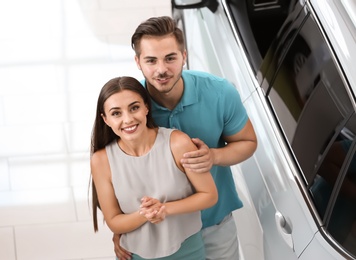 Happy couple buying new car in salon