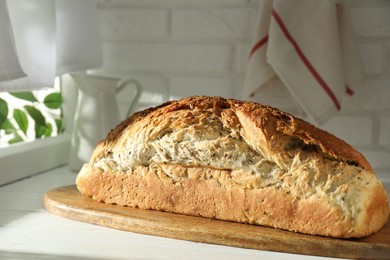 Photo of Freshly baked sourdough bread on white wooden table indoors