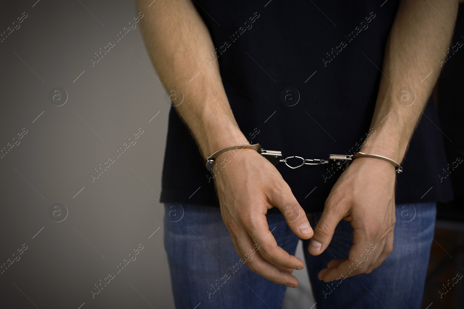 Photo of Man detained in handcuffs indoors, space for text. Criminal law