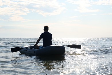Photo of Man rowing inflatable rubber fishing boat on sea, back view. Space for text
