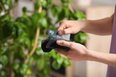 Woman using modern payment terminal indoors, closeup