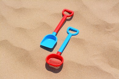 Photo of Plastic shovel and sieve on sand, above view. Beach toys