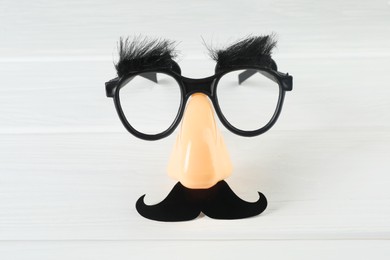 Funny mask with fake mustache, nose and glasses on white wooden background, top view