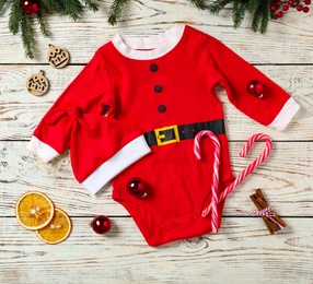 Flat lay composition with cute Christmas baby clothes on white wooden background