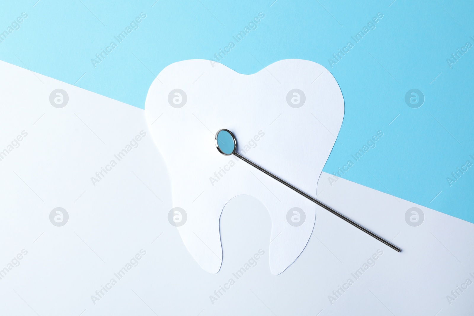 Photo of Paper tooth and dentist mirror on color background, top view