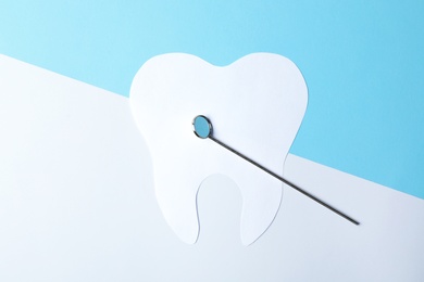 Paper tooth and dentist mirror on color background, top view