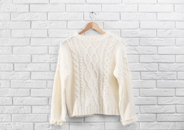 Hanger with stylish sweater on brick wall