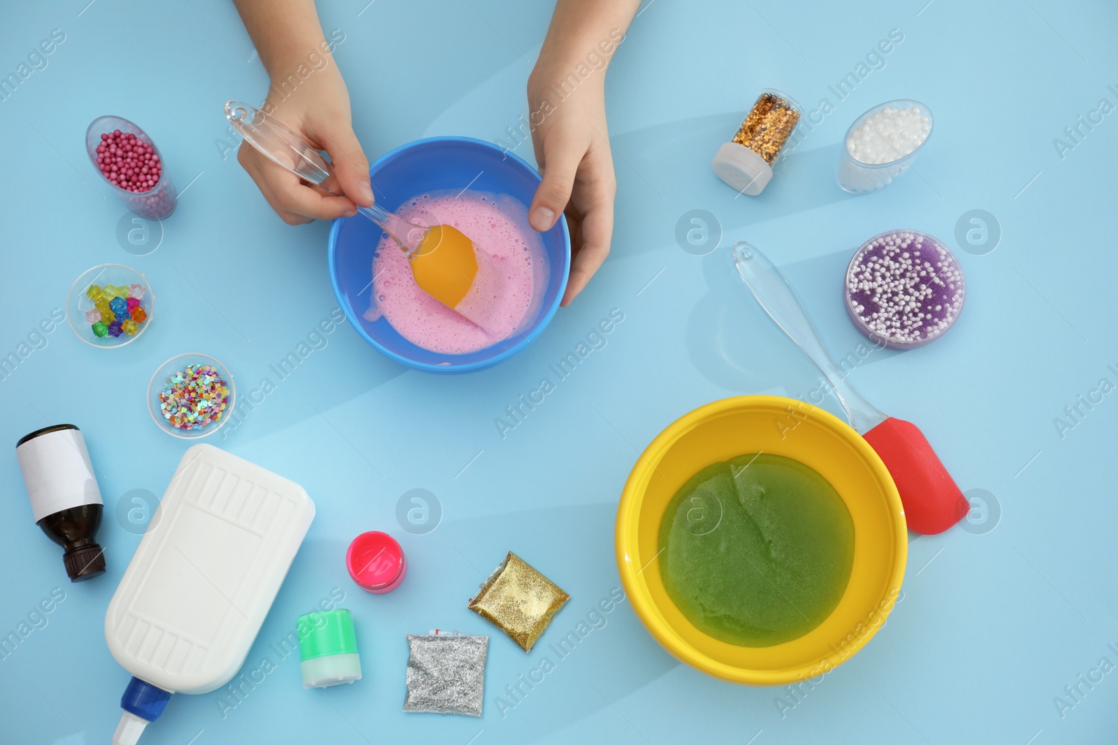 Photo of Little girl making slime toy on light blue background, top view