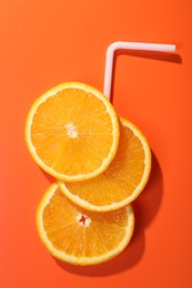 Photo of Slices of juicy orange and straw on terracotta background, top view