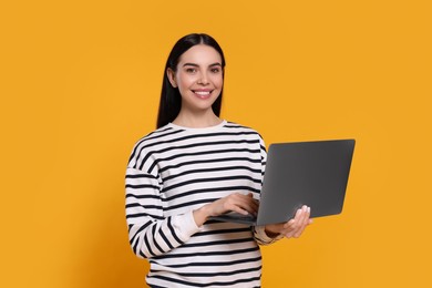 Photo of Happy woman with laptop on orange background