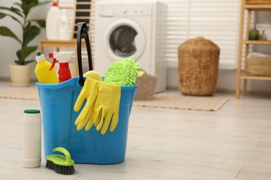 Photo of Different cleaning products and bucket on floor indoors, space for text