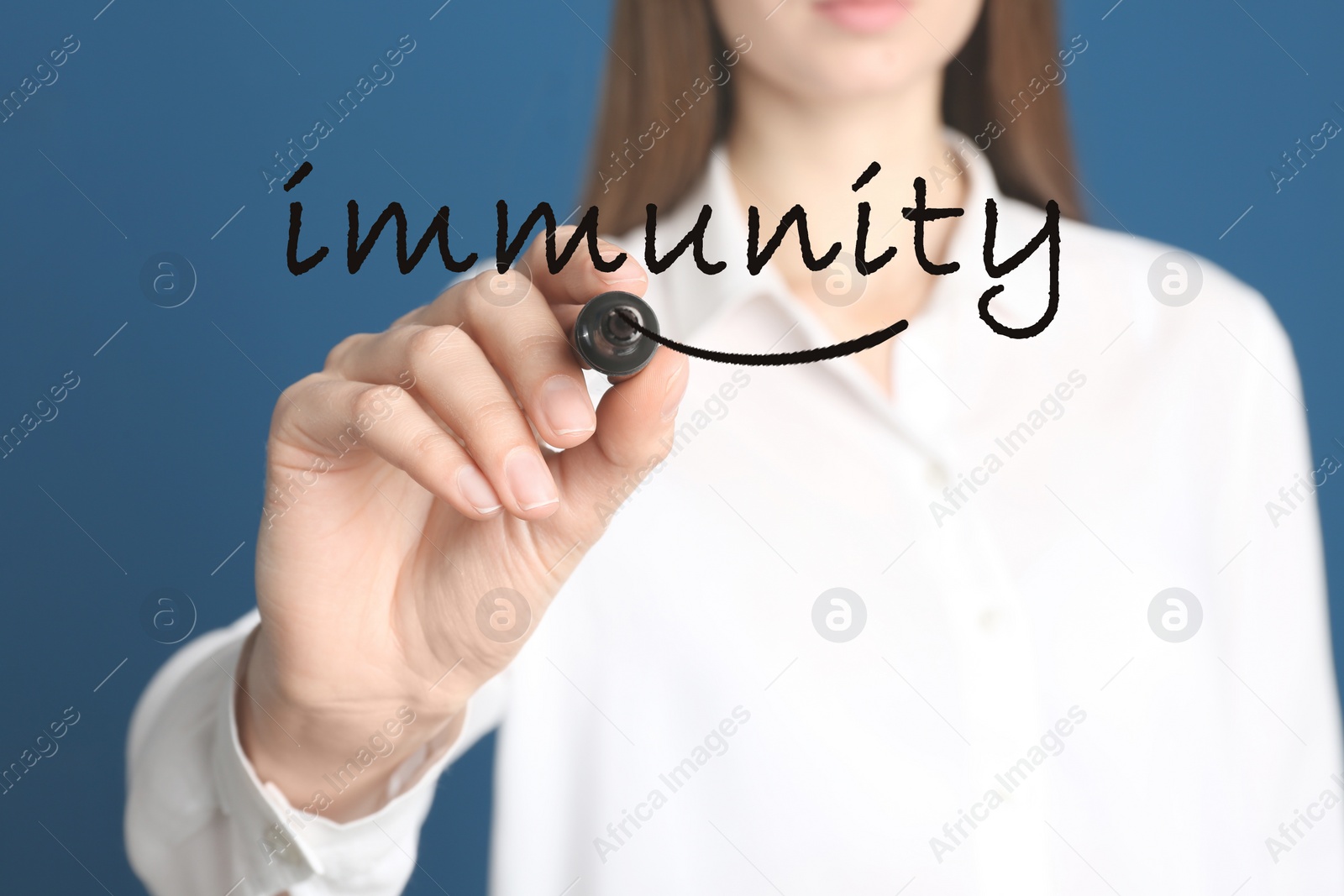 Image of Woman drawing line under word Immunity on transparent board, closeup