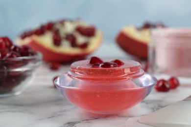 Photo of Cosmetic product made of pomegranate on white marble table, closeup. DIY beauty recipe