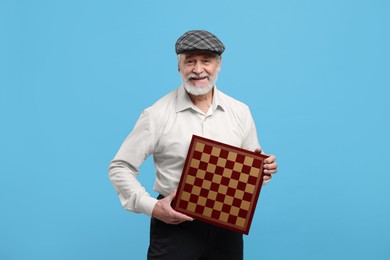 Photo of Man with chessboard on light blue background