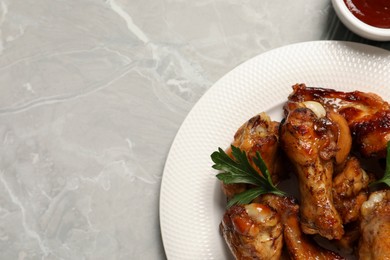 Photo of Plate with delicious fried chicken wings on light gray table, top view. Space for text
