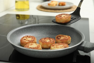 Frying delicious cottage cheese pancakes in kitchen, closeup