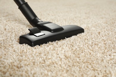Photo of Removing dirt from beige carpet with modern vacuum cleaner, closeup. Space for text