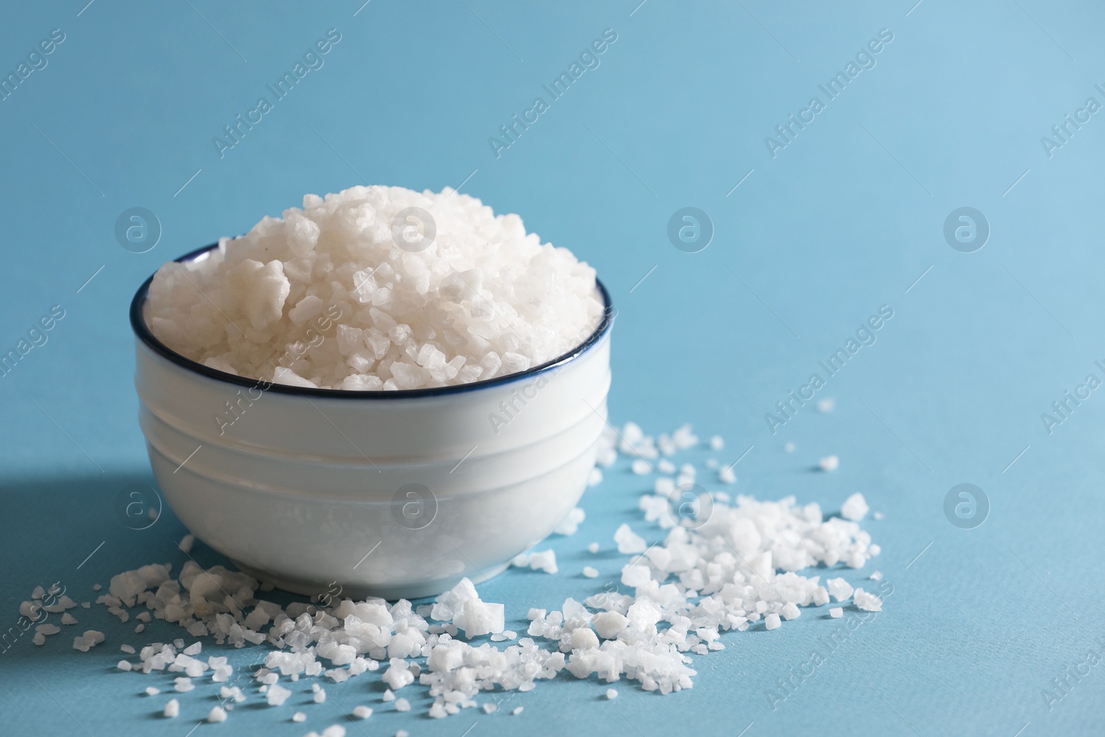 Photo of Organic salt in bowl on light blue background