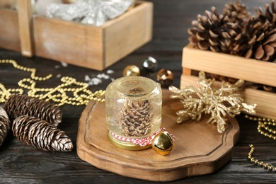Photo of Handmade snow globe and Christmas decorations on black wooden table