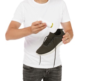 Photo of Man putting powder freshener into shoe on white background